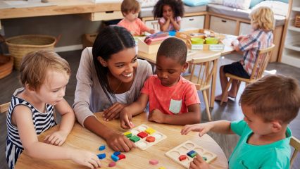 Children in a classroom sitting around a table with a teacher